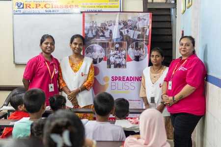 Spreading Bliss Foundation volunteers standing with children in a classroom during one of their educational support and awareness sessions in an underprivileged community.
 





