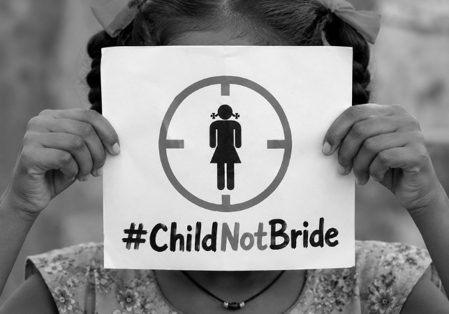 A girl holding a placard with the text Child Not Bride Spreading Bliss Foundation 
 

