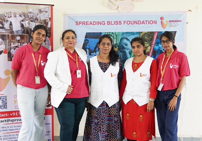 Spreading Bliss Foundation team members pose together in front of the organisation’s banner, showcasing their commitment to community welfare and social development. 