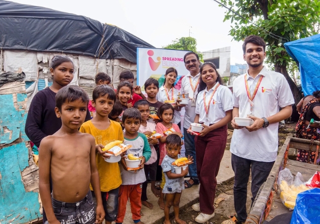 Spreading Bliss Foundation volunteers with smiling children holding freshly served meals during a food distribution drive.